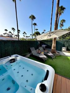 a jacuzzi tub on a patio with an umbrella at Chalet Privato con Jacuzzi New in Maspalomas