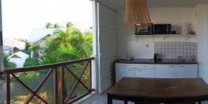 a small kitchen with a balcony with a table and a balcony at Le tamarin bleu - Studio à 300 m de la plage in La Saline les Bains