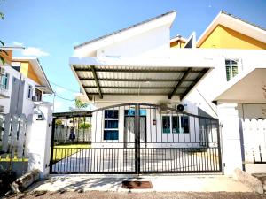 ein weißes Haus mit einem Tor und einem Zaun in der Unterkunft Fary Inn in Kampong Alor Gajah