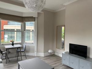 a living room with a television and a table and chairs at Strawberry Dale Apartment in Harrogate