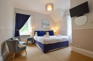 a bedroom with a bed with blue pillows and a chair at Strathnaver in Oban