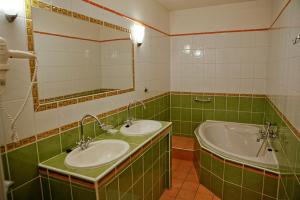 zielona i biała łazienka z 2 umywalkami i wanną w obiekcie Smolenický zámok w mieście Smolenice