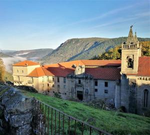 an old building on a hill with mountains in the background at La Casa de las rocas - Ribeira Sacra in Rubiacós