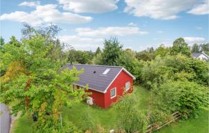 ein rotes Haus mit schwarzem Dach im Gras in der Unterkunft Gorgeous Home In Jgerspris With Kitchen in Jægerspris