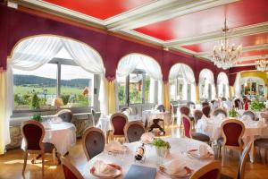 un restaurant avec des tables blanches, des chaises et des fenêtres dans l'établissement Hôtel-Restaurant Le Lac, à Malbuisson