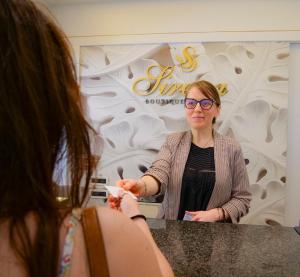 une femme debout devant un comptoir devant un miroir dans l'établissement Sirena Boutique Hotel, à Gabicce Mare