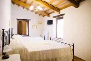 two beds in a bedroom with white walls and wooden ceilings at Locanda cireneo in Lugnano in Teverina