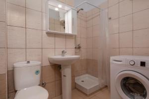 a bathroom with a toilet a sink and a washing machine at Kosmos Sevice Apartment Family 4A in Thessaloniki