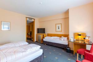 una habitación de hotel con 2 camas y una silla en Hotel Theresientor, en Straubing