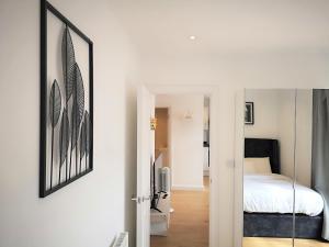 a white bedroom with a bed and a mirror at Clifton court hemel in Hemel Hempstead