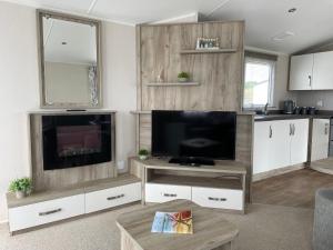 a living room with a flat screen tv and white cabinets at Fairview Caravan Hire in Lossiemouth