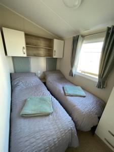 two beds in a small room with a window at Fairview Caravan Hire in Lossiemouth