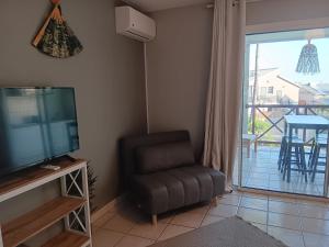 a living room with a television and a chair and a balcony at Le tamarin bleu - Studio à 300 m de la plage in La Saline les Bains