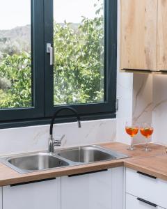 een keuken met een wastafel en 2 glazen wijn bij Arbona Apartment II in Vóroi