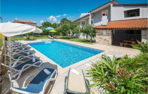 a swimming pool with chairs and an umbrella at Nice Home In Buje With Outdoor Swimming Pool in Buje