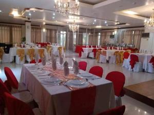 un gran salón de banquetes con mesas blancas y sillas rojas en Aberrise Country Villa Pension Hotel, en Dumaguete