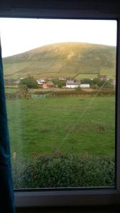 a view of a field of grass from a window at Three Sisters Holiday Home - 7km to Dingle in Ballyferriter