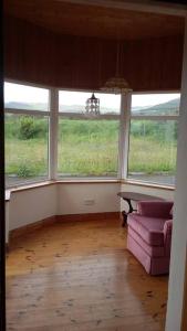 a living room with a couch and two windows at Three Sisters Holiday Home - 7km to Dingle in Ballyferriter