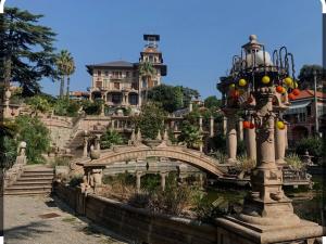 a bridge in a garden with a building in the background at La Bici Bianca in Imperia