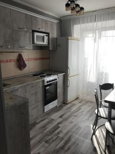 Il comprend une cuisine équipée d'une cuisinière et d'un réfrigérateur. dans l'établissement Двухкомнатная квартира рядом Парк Афганцев Телеценр Вокзал, à Pavlodar