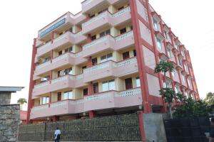 Un grand bâtiment rouge avec un homme debout devant lui dans l'établissement MAXIMILIAN HOMES, à Kilifi