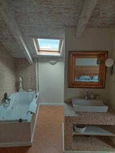 La salle de bains est pourvue d'une baignoire, d'un lavabo et d'un miroir. dans l'établissement Casa Algarviana, à São Bartolomeu de Messines