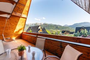 a table and chairs on a balcony with a view of mountains at Apartamenty Snowbird Zakopane in Kościelisko