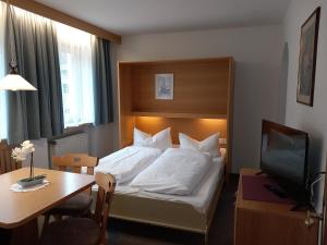 a bedroom with a bed and a desk and a television at Residence Alpenrose in Sesto