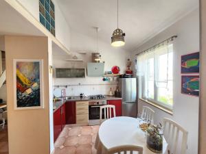 Apartment Lucija 2 في روفينج: مطبخ مع دواليب حمراء وطاولة بيضاء مع غرفة طعام