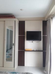 a bedroom with a tv on a wall with shelves at Gateway In pasteur in Bandung