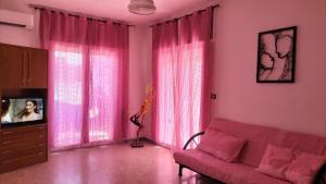 un soggiorno con tende rosa e divano di Casa Vacanza Casale a Brindisi