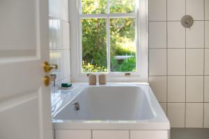 eine weiße Badewanne in einem Badezimmer mit Fenster in der Unterkunft Greenhill Farm Parklands Cottage - 2 bedroom 4 guests - Private House in Plettenberg Bay + 30 Fotos