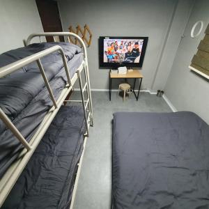 a room with two bunk beds and a desk with a television at Seven Hostel in Seoul
