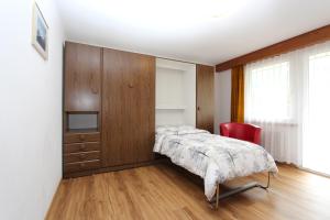ein Schlafzimmer mit einem Bett, einem Schrank und einem Stuhl in der Unterkunft Haus Primavera in Saas-Fee