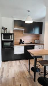 uma cozinha com armários pretos e uma mesa de madeira em Les Treilles de Salies - Studio au calme em Salies-de-Béarn