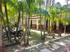 une moto garée devant une maison avec des palmiers dans l'établissement Hospedagem e queijaria Péua, à Soure