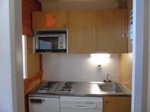 a small kitchen with a stove and a microwave at Studio Valfréjus, 1 pièce, 4 personnes - FR-1-561-63 in Valfréjus