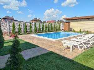 a swimming pool with lounge chairs next to a yard at Дом с бассейном и сауной in Boryspilʼ