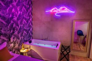 a bathroom with a tub and a neon sign on the wall at Live suite Napoli in Naples
