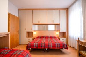 a bedroom with a bed with a red plaid blanket at Residence Villa Viola in Andalo
