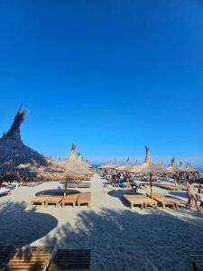 a beach with many straw umbrellas and people on it at Summer Crib Mamaia-Sat in Mamaia Sat/Năvodari