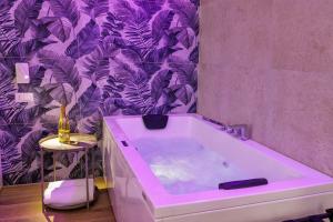 a bathroom with a tub with a purple wallpaper at Live suite Napoli in Naples