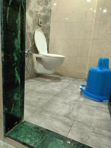 a bathroom with a toilet and a blue bucket at Kohinoor Dormitory in Mumbai