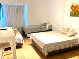 Habitación con 3 camas, mesa y escritorio. en Apart hotel Ciudad de Bs As en Buenos Aires