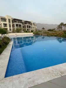 Jebel Sifah Golf View Apartment في مسقط: مسبح ازرق كبير امام مبنى