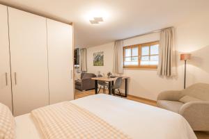 a bedroom with a bed and a chair and a table at Landhaus Wiederkehr in Oberstdorf