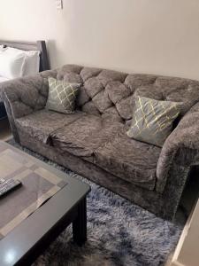 a brown couch in a living room with a table at Blue Falls Queen Studio in Nairobi