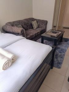 a bed in a room with a couch and a table at Blue Falls Queen Studio in Nairobi