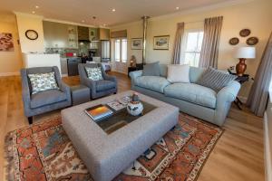 ein Wohnzimmer mit einer Couch und zwei Stühlen und einem Tisch in der Unterkunft Greenhill Farm Parklands Cottage - 2 bedroom 4 guests - Private House in Plettenberg Bay