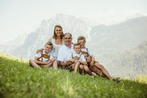 a family sitting on a hill in the grass at Hotel Mareo Dolomites in San Vigilio Di Marebbe
